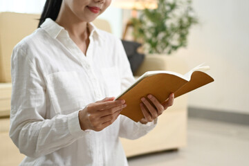 A woman is reading a book in a living room.