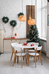 Cozy holiday dining area illuminated by warm lights with a Christmas tree in a bright, modern space