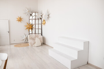 Bright and airy interior with minimalistic decor, featuring geometric stars and a cozy seating area near the sunlight window