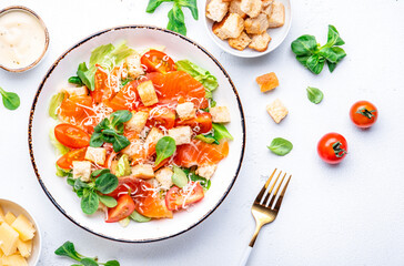 Foodie food salad with salmon, iceberg and lumb lettuce, croutons, parmesan cheese and caesar dressing. White background, top view