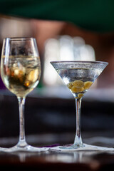 Martini with olives next to glass of white wine