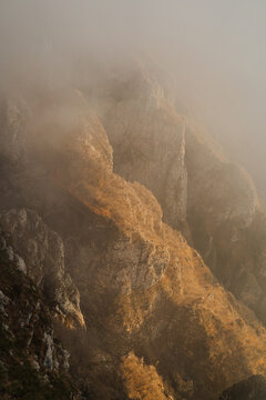 Closeup of a golden brown mountain covered in the cloud