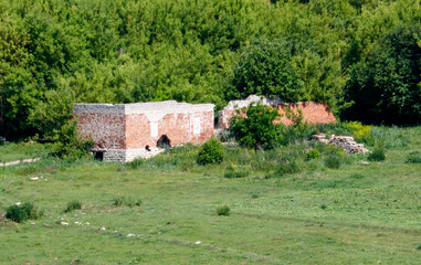 A brick building is in the middle of a grassy field