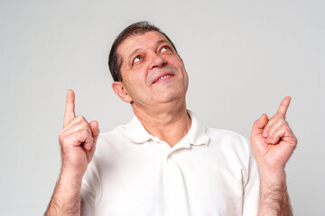 Man in a white shirt pointing upwards with a thoughtful expression in a neutral setting