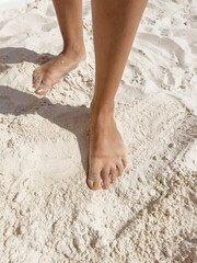 A woman's feet are in the sand, and she is walking
