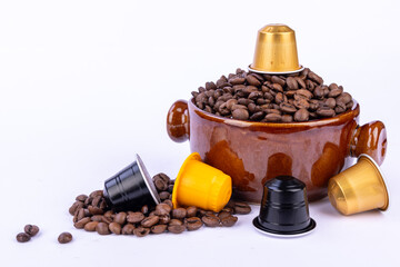 Brown bowl filled with coffee beans and colorful coffee capsules on a white background, scattered beans around the bowl for a cozy ambiance