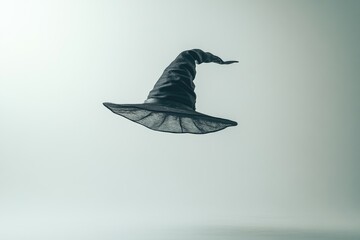 Fototapeta premium A Black Witch's Hat Floating in Mid-Air Against a White Background