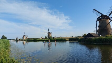 A few people are paddle boarding in the river in Kinderdijk.