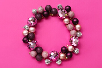 Frame made of Christmas tree balls on pink background