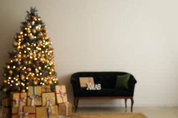 Blurred view of festive living room with Christmas tree, gift boxes, sofa and glowing lights