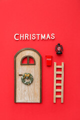 Beautiful composition with door, ladder and Christmas decorations on red background
