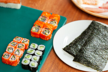 Freshly made sushi rolls with colorful vegetables sitting on a green cutting board
