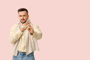 Obraz premium Sick young man with thermometer on pink background