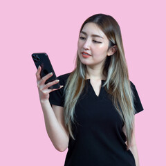 Young asian woman in casual clothing, holding and looking at a smartphone. Portrait on a simple pink background with studio light. Isolated