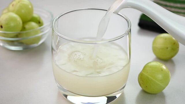 Serving amla juice also called as Indian gooseberry juice in a cup.