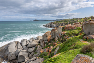 The seaward side of Granite Island with grass and a jumble of orange tinted granite boulders...