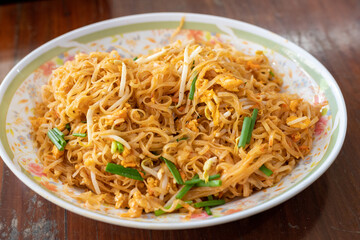 A plate of noodles with green and yellow vegetables on top