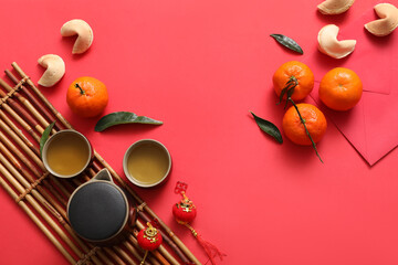 Composition with bamboo mat, tea set, tangerines and Chinese symbols on red background. New Year celebration