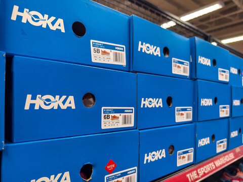 Stack of blue Hoka shoe boxes in a sports outlet store
