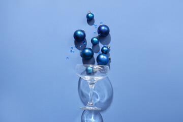 Champagne glass with Christmas balls and glitters on blue background