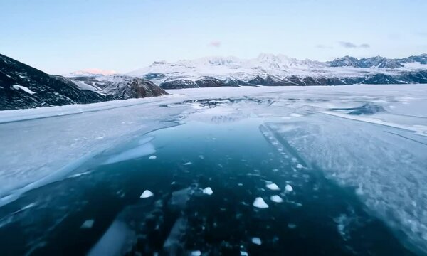 Swift FPV Traverse through a stunning Alaskan tundra, sweeping snowfields and icy lakes, weaving between rugged peaks and serene frozen landscapes.