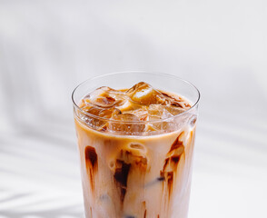Refreshing iced coffee with milk and chocolate syrup on white background