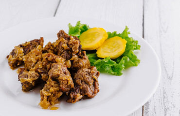 Delicious beef stew with potatoes and onions lying on white plate on white background
