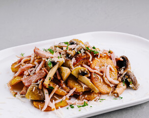 Roasted potatoes with bacon and mushrooms on white plate