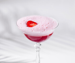Strawberry cocktail with pink foam standing on white background