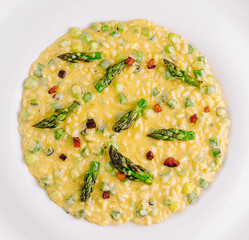 Delicious risotto with asparagus and pancetta being served on white plate