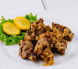 Delicious beef stew with potatoes and onions lying on white plate on white background