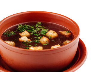 Hot soup with croutons and herbs served in brown bowl