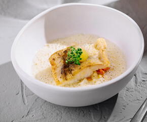 Gourmet fish fillet in creamy sauce on stone background