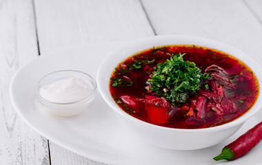 Traditional ukrainian russian borscht soup with sour cream and pepper on white wooden background