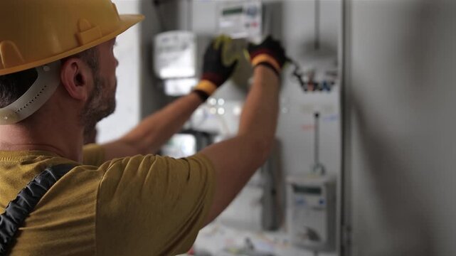 Technician working on a electricity power meter station in a building.	
