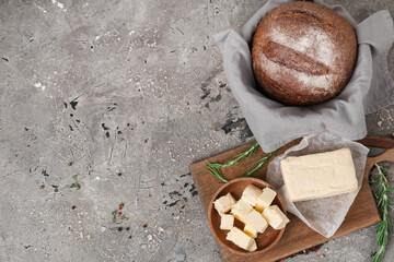 Composition with fresh bread, butter and rosemary on grunge background