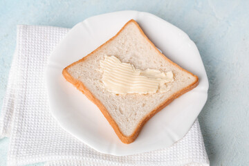 Plate with toast and butter on color table
