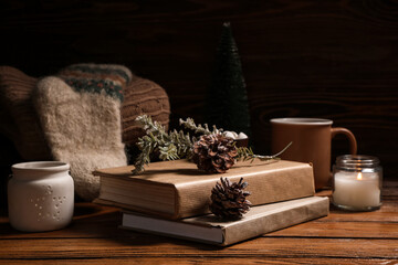 Beautiful composition with books, winter decorations, cup of tea and warm clothes on brown wooden background
