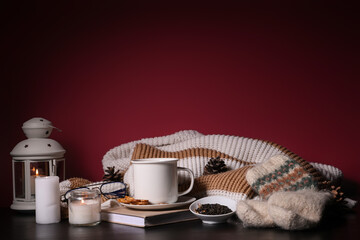 Beautiful winter composition with book, cup of tea, Christmas decorations and warm clothes on red background
