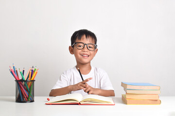 Portrait of an Asian boy studying and holding a pencil with a happy expression isolated on a white background