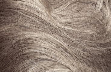 Blond hair close-up as a background. Women's long light brown hair. Beautifully styled wavy shiny...