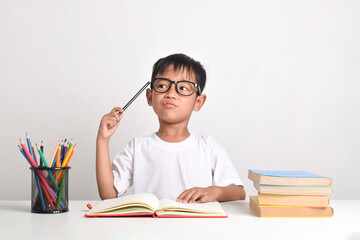 Portrait of an Asian boy studying with a thinking expression isolated on a white background