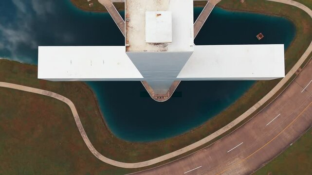 An aerial view of a huge white Christian Cross, in front of a church, recorded at 60 frames per second