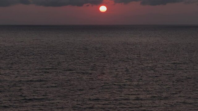 A Stunning View of the Sunset Over the Sea With a Dark, Dense, Cloudy Sky in Salento, Apulia, Italy - Pan Up Shot