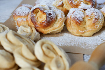 Close-up of homemade puff pastry buns with powdered sugar on wooden table