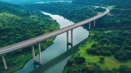 Obraz premium Elevated road bridge spanning green river valley, surrounded by lush verdant trees and hills