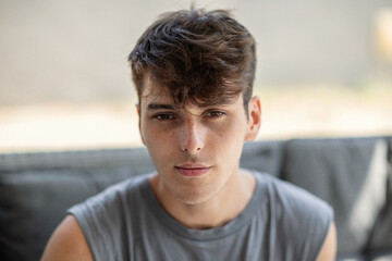 Fototapeta premium Portrait of handsome young man sitting on sofa and looking at camera and smiling