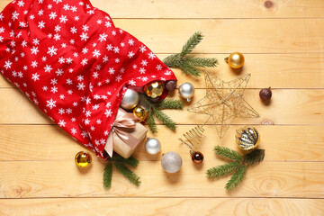 Santa bag with Christmas decorations, gift box and fir branches on wooden background