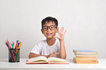 Portrait of an Asian boy studying isolated on a white background. Raising his hand to answer a question