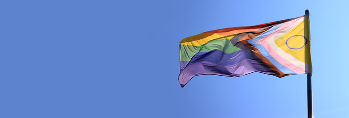 Intersex-inclusive redesign of the Progress Pride Flag. Rainbow LGBT flag against a blue sky. Flag...